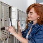positive casually dressed woman holding new letter from postal delivery getting her post out her letterbox 657921 1045